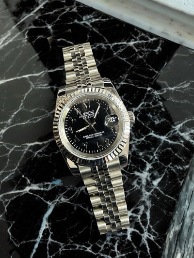 Silver Seiko watch on a black marble surface