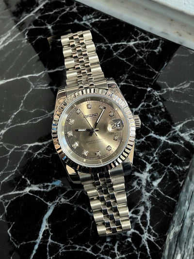 Silver watch with a detailed face on a black marble surface