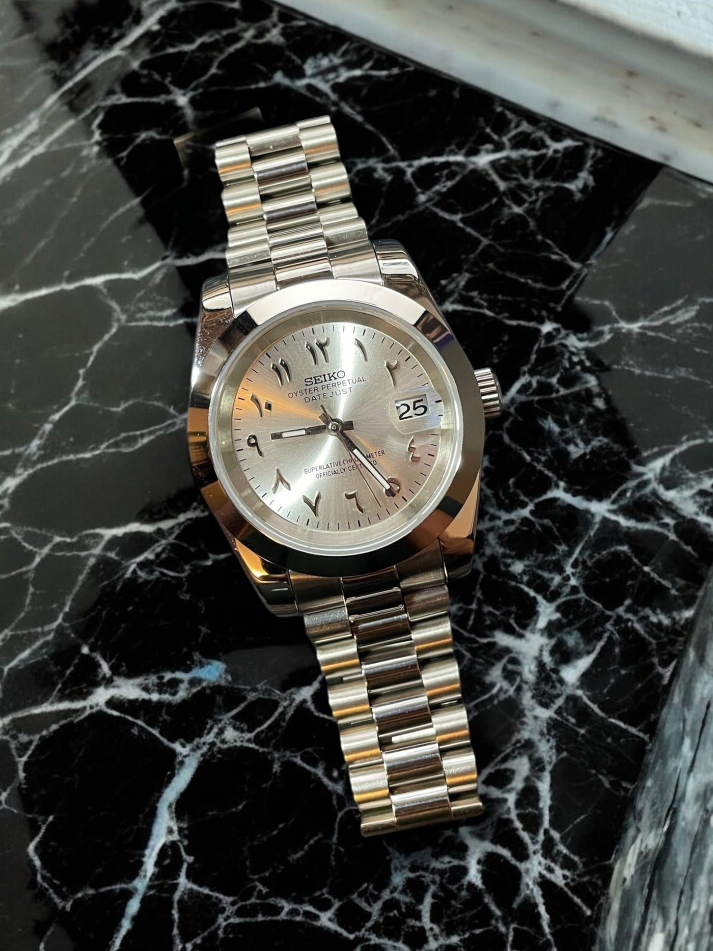 Silver Seiko watch on a black marble surface