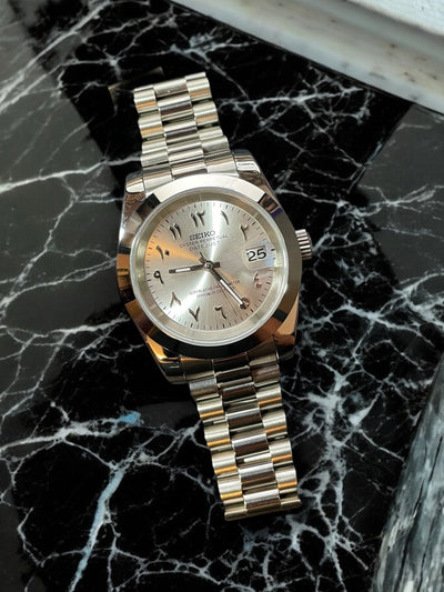 Silver Seiko watch on a black marble surface