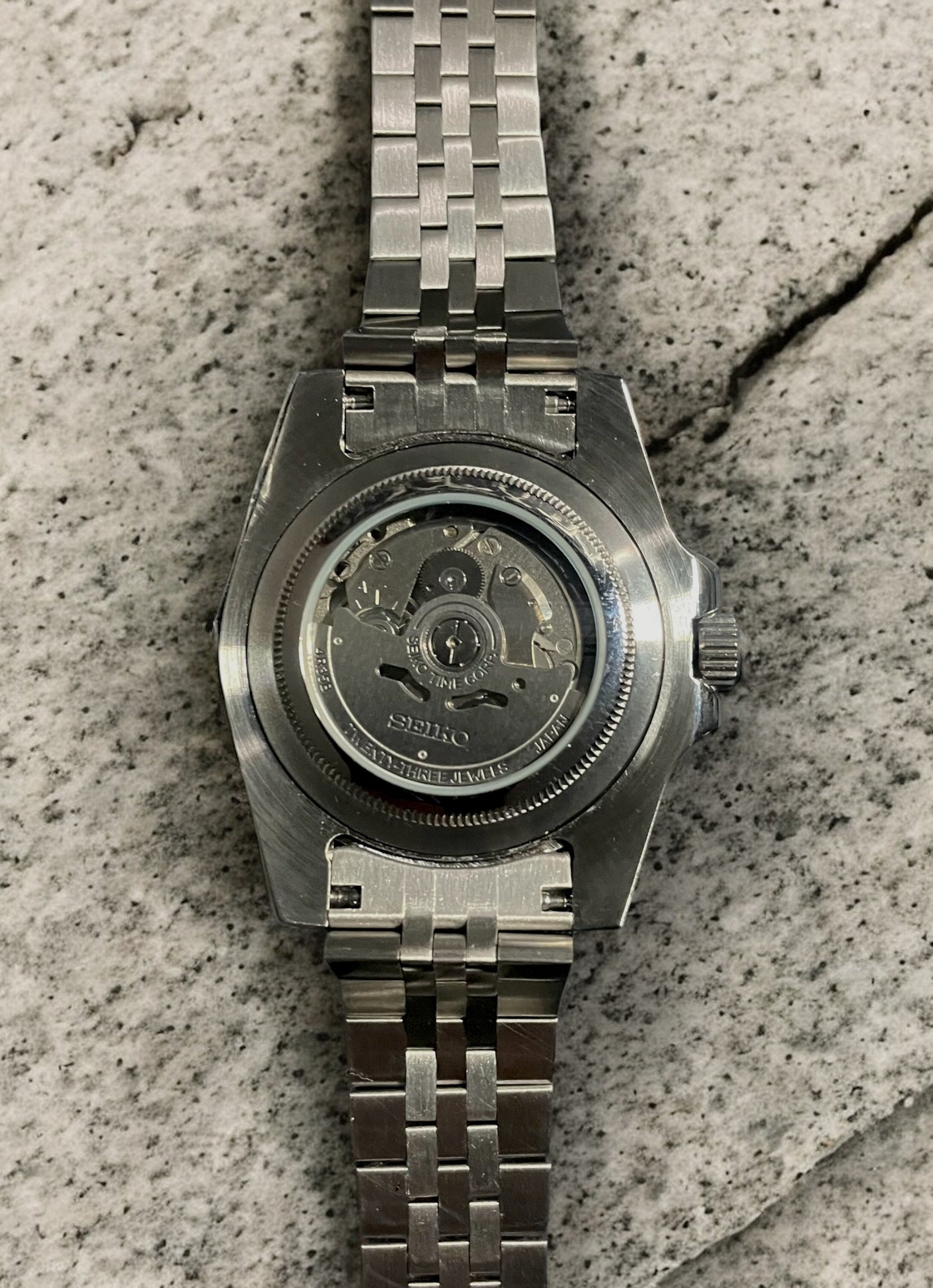 Silver watch with a detailed mechanism on a textured surface