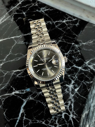 Luxury watch with a gold and silver band on a black marble surface