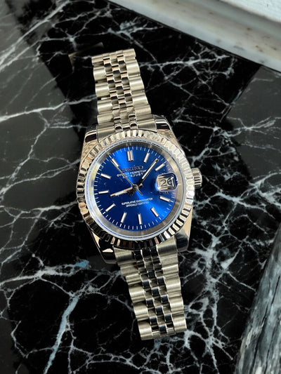 Gold watch with a blue face on a black marble surface