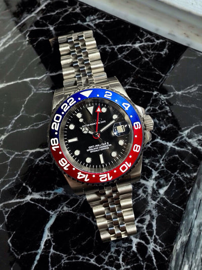Watch with a distinctive red and blue bezel on a black marble surface