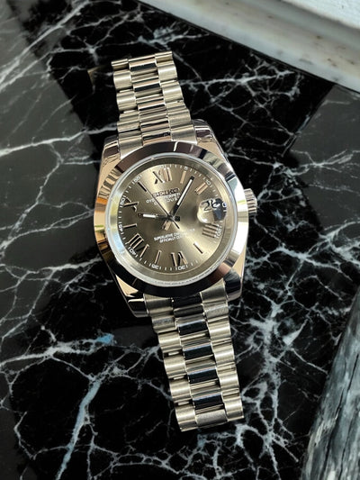 Silver watch with a dark face on a black marble surface