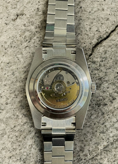 Silver watch with mechanical movement on a textured surface