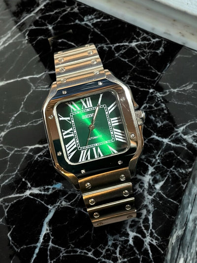 Gold watch with green face on a black marble surface