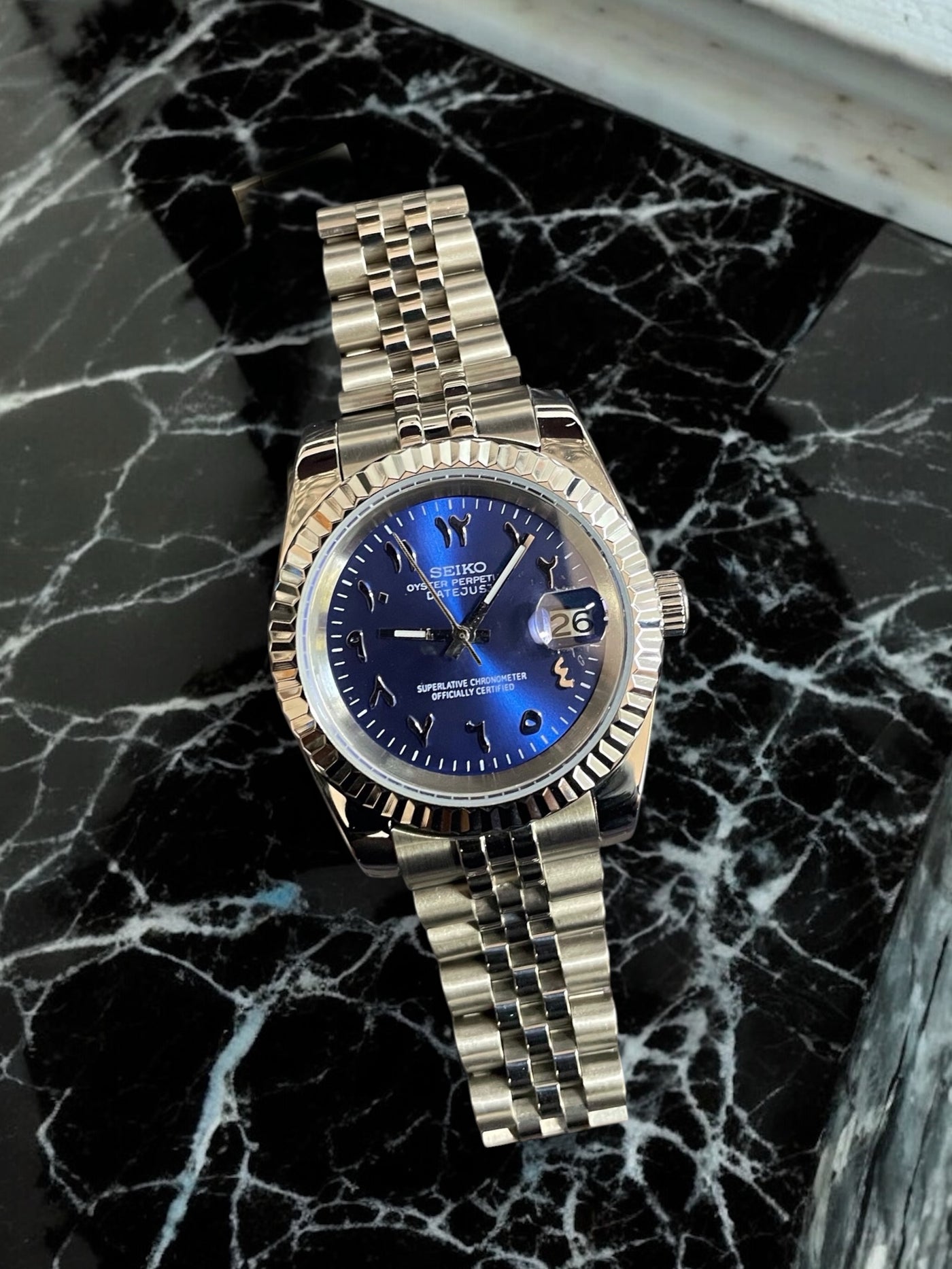 Gold watch with a blue face on a black marble surface