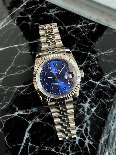 Gold watch with a blue face on a black marble surface