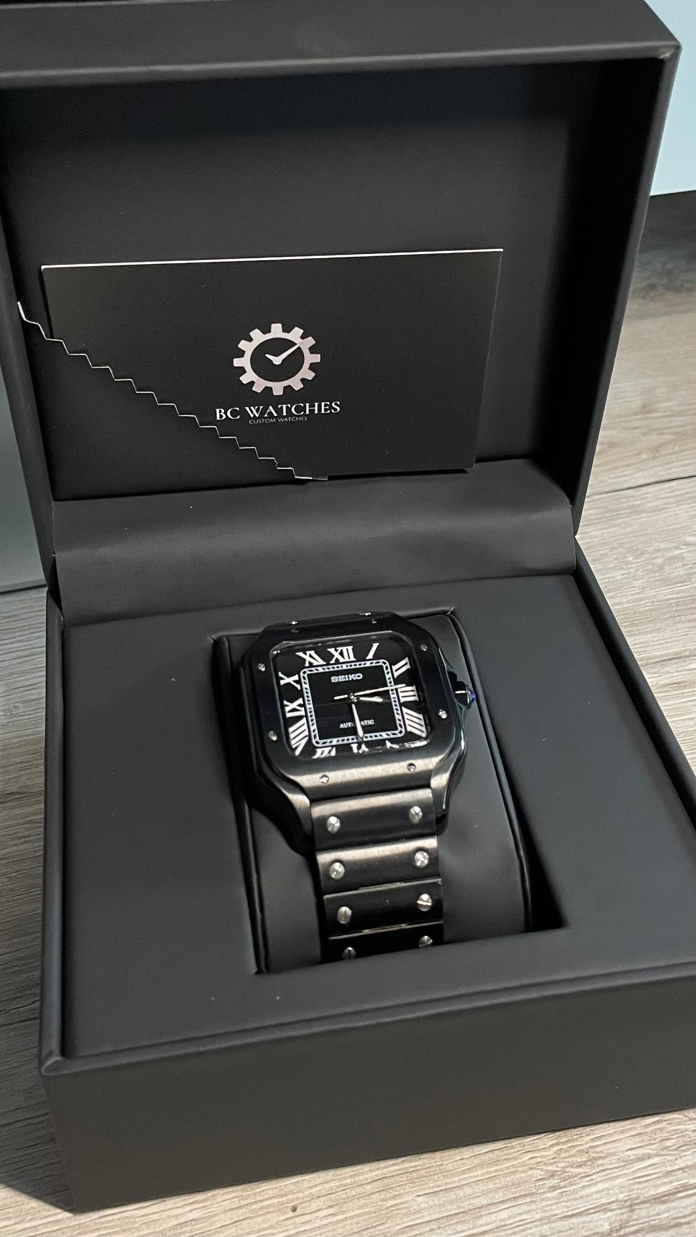 Black digital watch in a branded box on a wooden surface