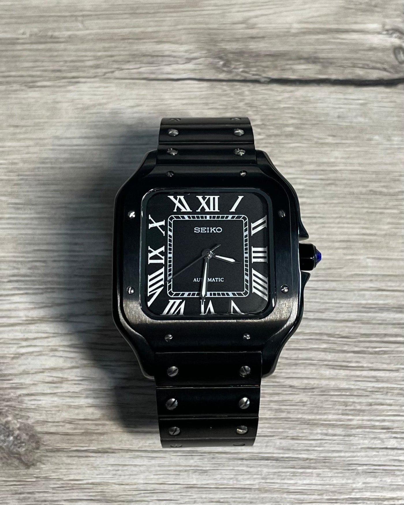 Black watch with a detailed face on a wooden surface