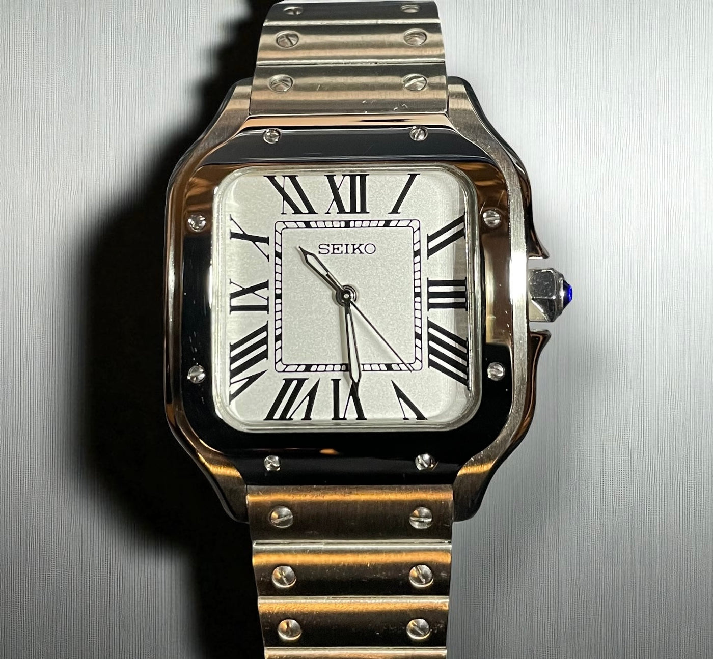 Silver Seiko watch with a metallic band on a reflective surface