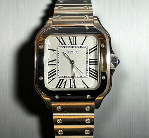 Silver Seiko watch with a metallic band on a reflective surface