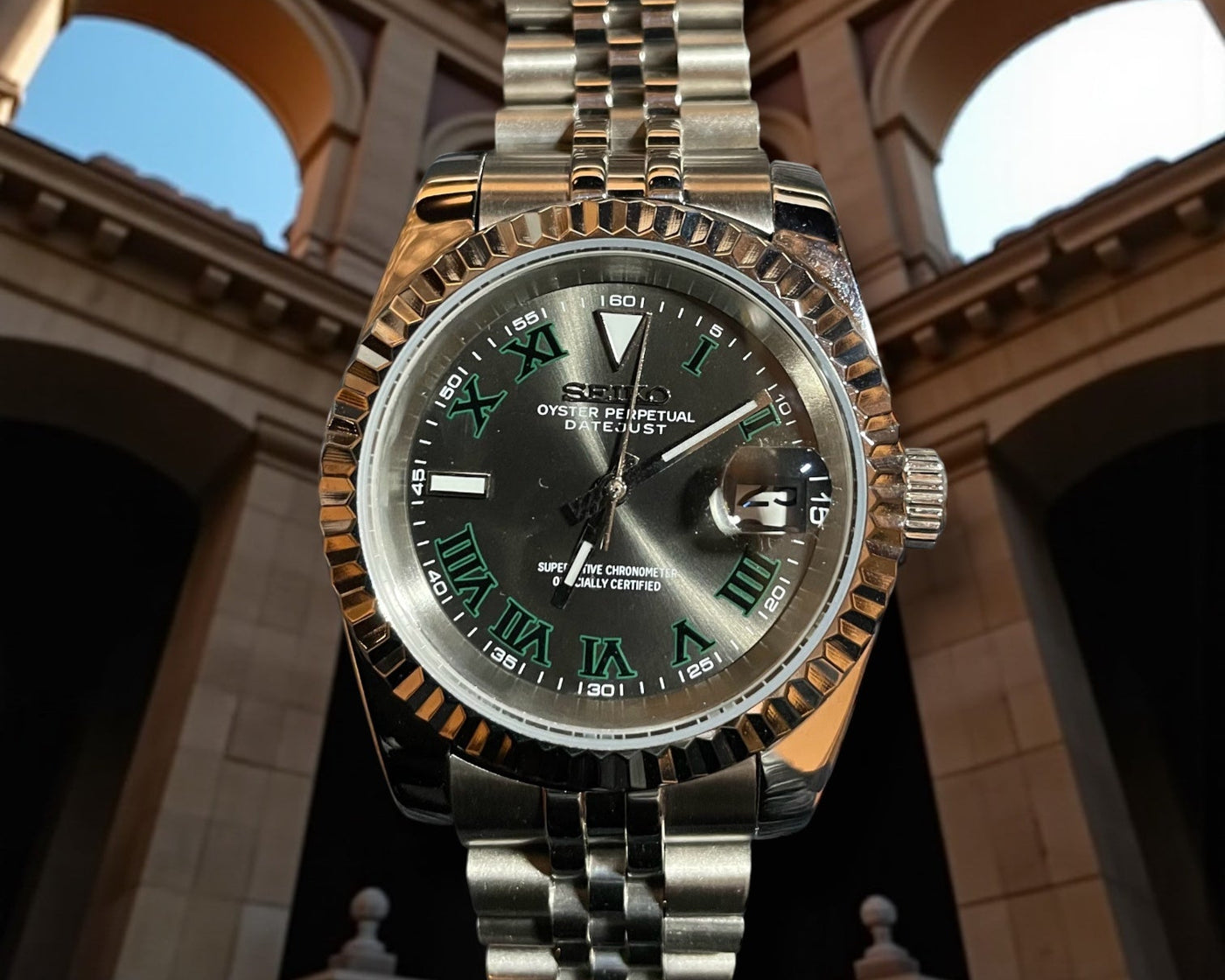 Silver watch with a detailed face against an architectural background
