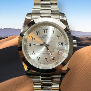 Silver Seiko watch on a wrist with a desert landscape in the background